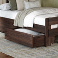 Dark walnut wooden storage bed with pull-out trundle drawer, white quilted bedding, beige knit throw and neutral decorative pillows