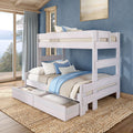 Whitewashed wooden bunk bed with pull-out under-bed storage drawers, blue and neutral bedding in a coastal bedroom with jute rug and lake-view window