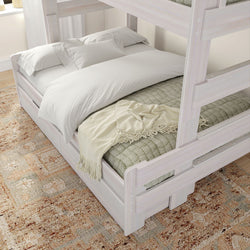 Wooden bunk bed with cozy pillows and blankets on a patterned rug in a bright room.