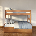 Modern wooden bunk bed with storage drawers, blue and white bedding and pillows in a sunlit minimalist bedroom