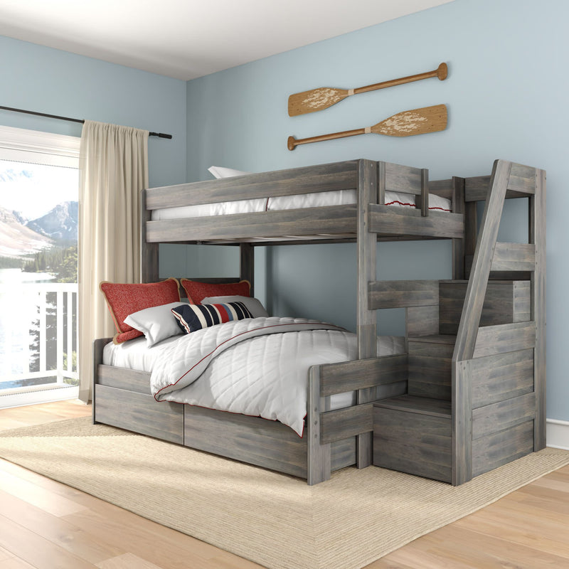 Gray rustic twin-over-full wooden bunk bed with built-in storage stairs and under-bed drawers in a coastal-style bedroom with light blue walls, nautical oar wall decor and large lake-view window