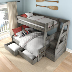 Gray washed wood twin-over-full bunk bed with built-in staircase and pull-out storage drawers, white quilted bedding and red nautical pillows in bright coastal bedroom
