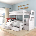 Whitewashed twin-over-full bunk bed with built-in storage drawers and staircase in coastal kids' bedroom with light blue walls and oar wall decor