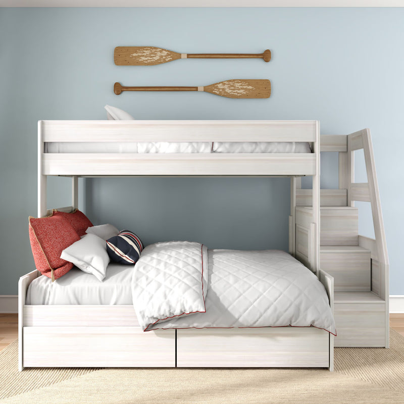 Coastal-style white wooden bunk bed with staircase storage, lower full bed with white quilt and red pillows on light-blue wall with decorative wooden oars