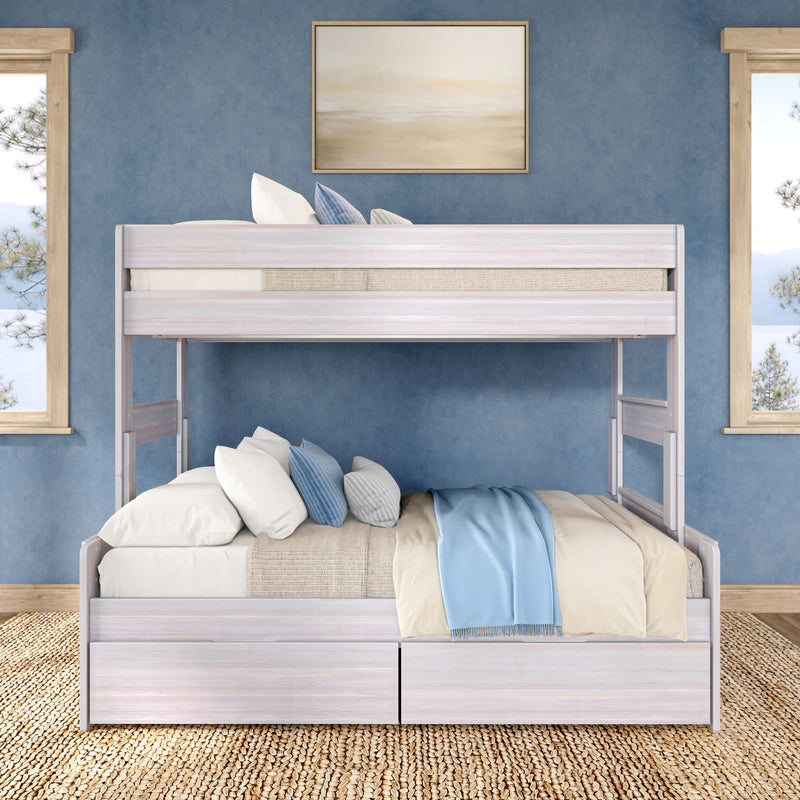 White wooden twin-over-full bunk bed with under-bed storage drawers, beige and blue bedding and pillows in a coastal blue bedroom with jute rug and windows