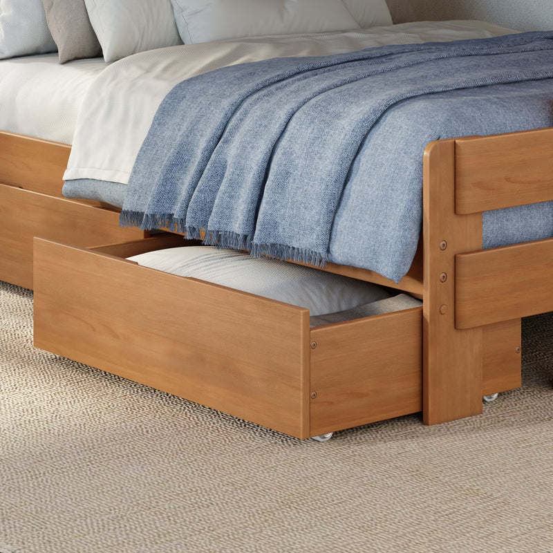 Wooden trundle bed with pull-out underbed storage drawer, blue woven throw blanket and white bedding in a modern space-saving bedroom