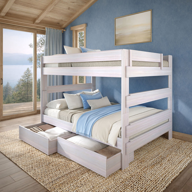 Whitewashed wooden full-over-full bunk bed with under-bed storage drawers in a coastal-style blue bedroom, layered neutral and blue bedding, natural light and lake view through sliding glass door