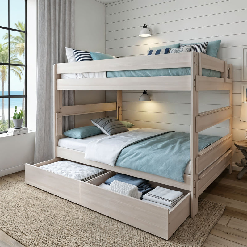 Whitewashed wooden bunk bed with built-in under-bed drawers, teal linens and coastal decor in sunlit bedroom by ocean-view window