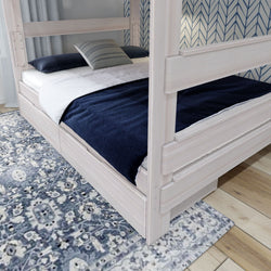 Modern wooden bunk bed with navy bedding and a decorative patterned rug in a stylish bedroom setting.