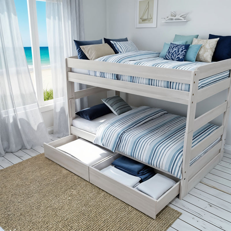 White wooden twin bunk bed with blue-striped bedding and pull-out under-bed storage in a coastal bedroom with ocean-view window