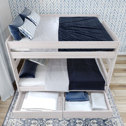 Modern white wooden bunk bed with navy blue bedding and under-bed storage drawers in a stylish room.