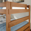 Solid natural wood twin bunk bed with safety rails, blue bedding and white pillows in a cozy modern bedroom interior