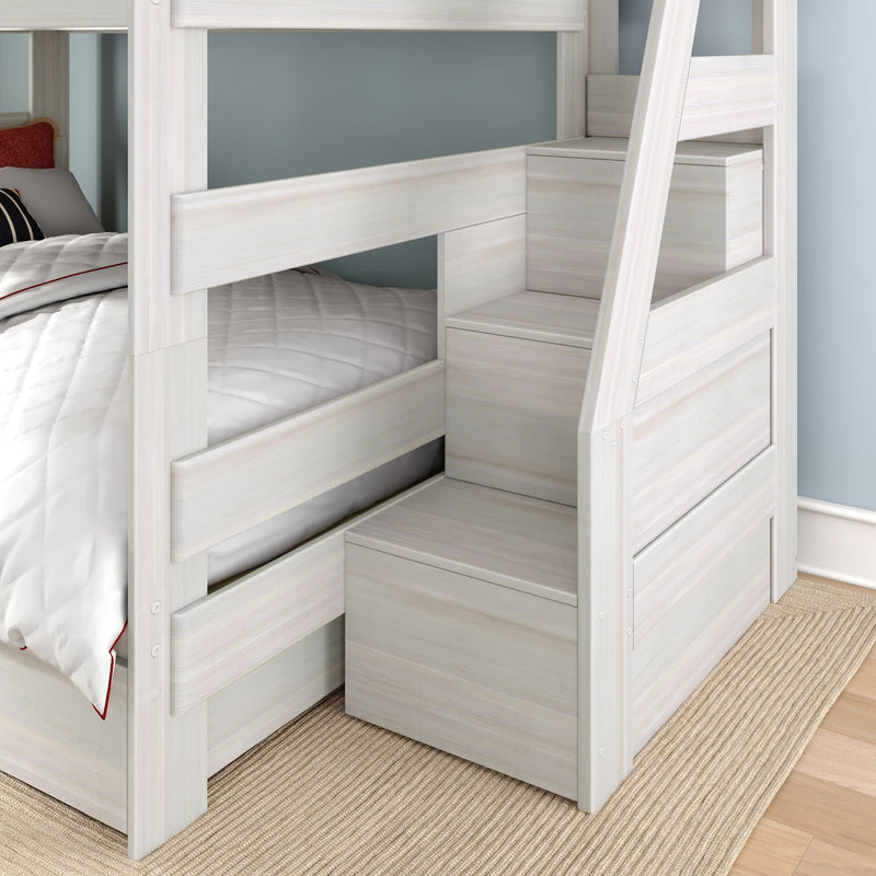 Whitewashed wooden twin-over-twin bunk bed with built-in storage staircase and drawers, quilted bedding, and natural fiber rug in a modern kids' bedroom