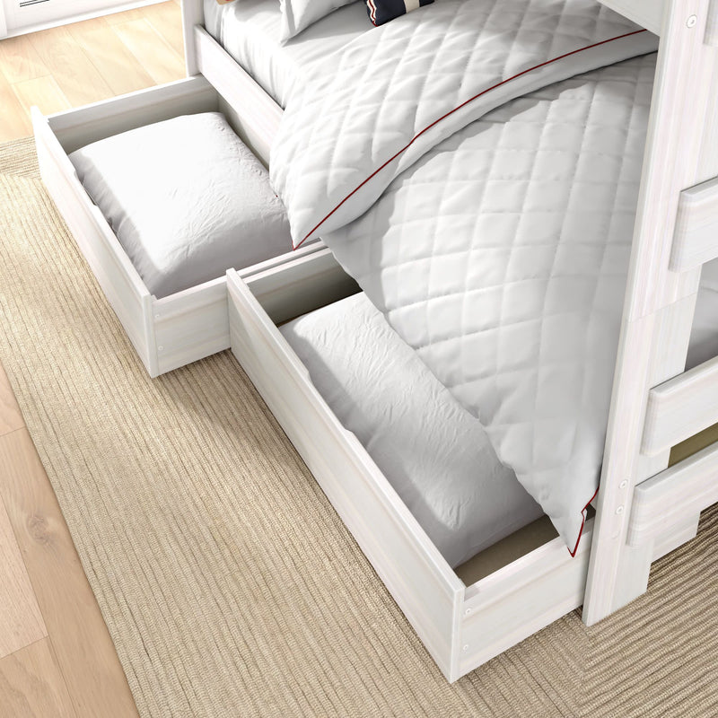 White wooden bunk bed with under-bed storage drawers holding pillows and quilted white bedding with red trim on a beige rug