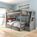 Gray rustic full-over-full wooden bunk bed with built-in storage staircase and under-bed drawers, white quilt and red accent pillows in coastal bedroom with oar wall decor and lake-view balcony