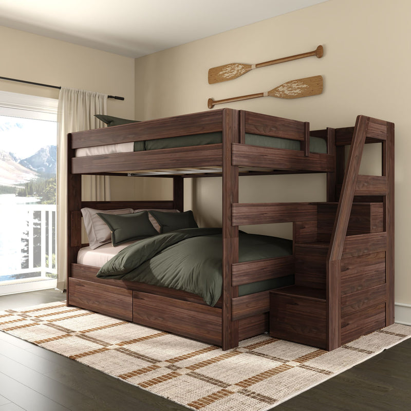 Dark walnut wooden bunk bed with staircase and built-in storage drawers in cozy lakeside bedroom featuring green bedding, decorative canoe paddles on the wall, large window with lake and mountain view, and plaid area rug