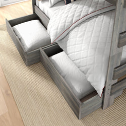 Gray wooden twin bunk bed with pull-out storage drawers holding pillows and white quilted bedding on a jute rug