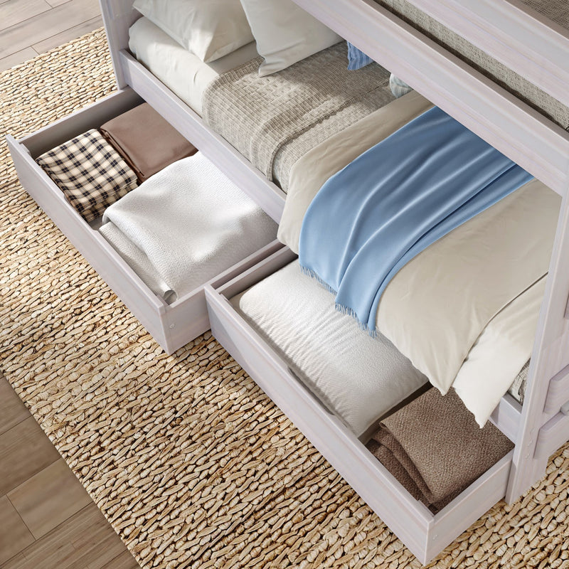 White wooden bunk bed with built-in under-bed storage drawers containing folded blankets, pillows and blue throw on a woven jute rug