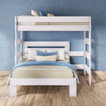 White wooden bunk bed with full-size lower bed, blue and beige bedding and striped pillows on light wood floor in modern blue bedroom