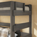 Gray solid wood twin-over-twin bunk bed frame close-up with guardrails and plaid pillow in cozy farmhouse bedroom