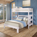 Whitewashed wooden bunk bed with blue and beige linen bedding in a coastal-style bedroom featuring a textured blue wall, large window and sheer curtains