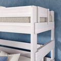 Whitewashed twin-over-twin bunk bed with safety rails and knit mattress against blue textured wall