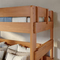 Solid wood bunk bed with natural finish, close-up of top guardrail, mattress and textured white pillows in modern kids' bedroom