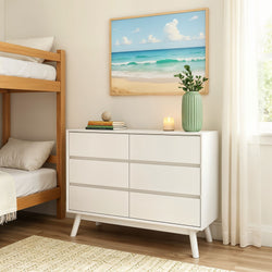 Contemporary bedroom interior with white dresser, ocean artwork, and a candle on top, next to a wooden bunk bed.