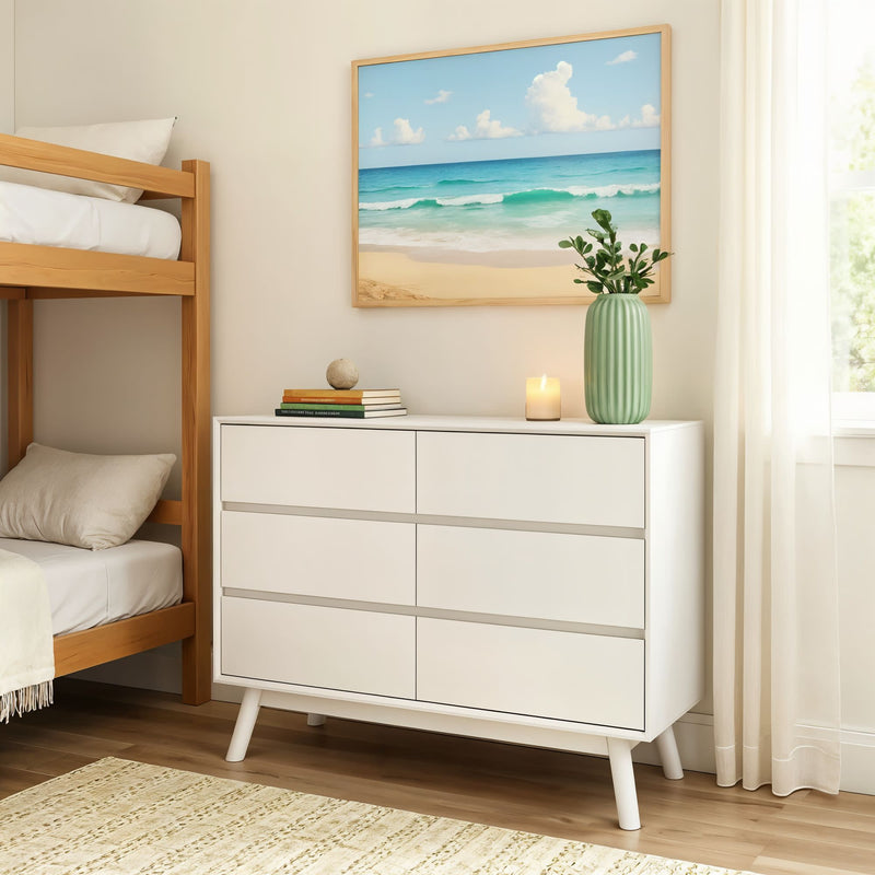 Contemporary bedroom interior with white dresser, ocean artwork, and a candle on top, next to a wooden bunk bed.