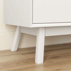 Modern white cabinet with sleek wooden legs on a light wood floor.