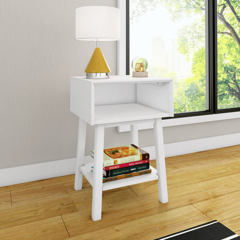 White side table with lamp and books in modern living room with large window view.