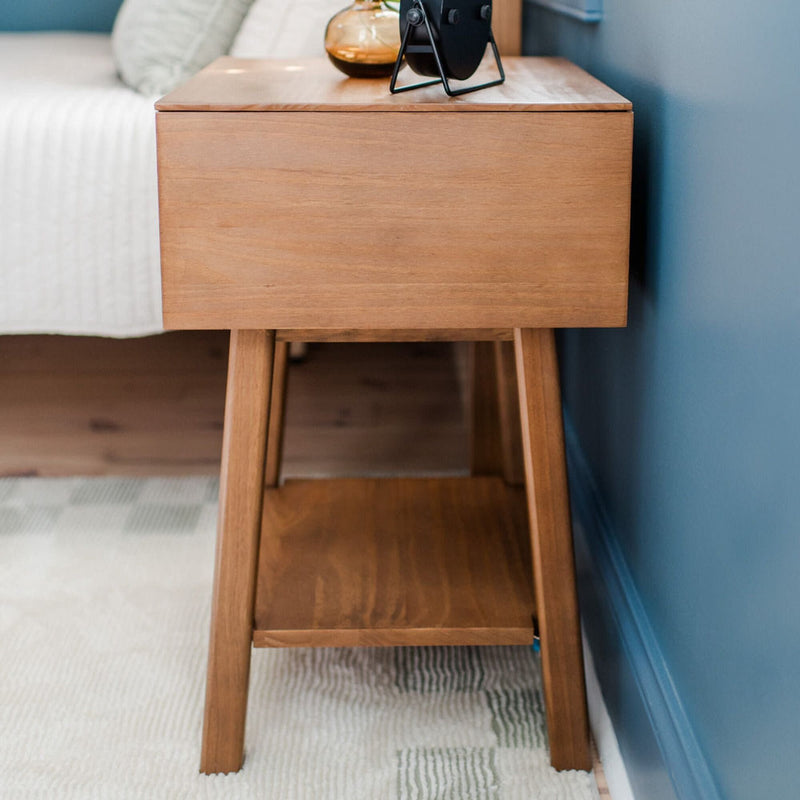 Modern wooden bedside table with decorative accents on a patterned rug.
