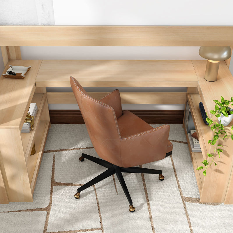 Modern home office workspace with brown leather swivel chair, light wood L-shaped desk, brass task lamp, potted trailing plant and neutral geometric rug