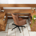 Modern home office workspace with camel leather swivel chair, L-shaped walnut desk with built-in shelves, brass-accented casters, table lamp, trailing potted plant and neutral geometric rug