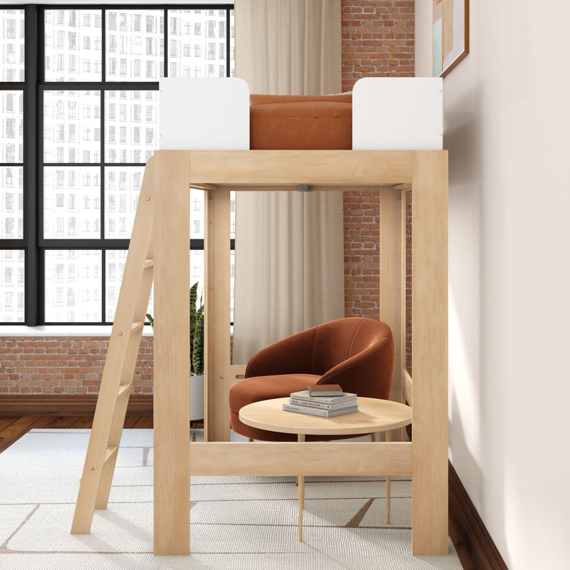 Wooden loft bed with ladder above cozy reading nook with rust velvet armchair, round coffee table, books, exposed brick and large windows