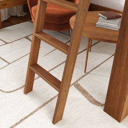 Wooden ladder beside orange armchair in modern living room with white patterned rug.