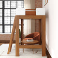 Wooden loft bed with ladder above a cozy reading nook featuring an orange velvet armchair, round wooden side table with books, exposed brick wall and large industrial window, modern space-saving loft bedroom