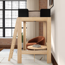 Modern wooden loft bed with ladder and cozy under-bed reading nook featuring a rust-orange armchair, round coffee table, stacked books, exposed brick wall and large industrial windows
