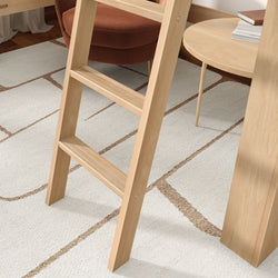 Light wood ladder beside round side table and rust velvet chair on white geometric area rug in modern Scandinavian living room
