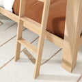 Light natural wood bunk bed ladder attached to loft bed with brown bedding on a beige geometric area rug