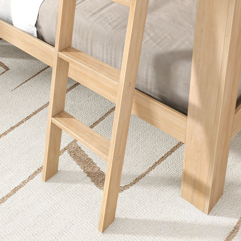 Close-up of wooden bunk bed ladder and light oak bed frame with slatted steps and natural finish on a beige geometric rug