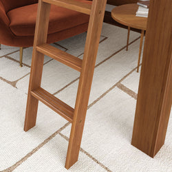 Wooden ladder next to mid-century modern furniture on patterned white rug.