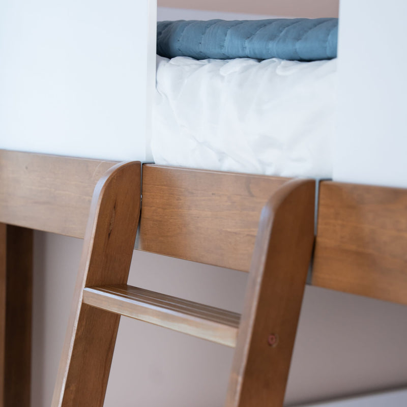 Close-up of solid wood bunk bed ladder and railing with white mattress and blue quilt, modern space-saving children’s bedroom bunk bed