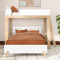 Modern light wood bunk bed with ladder and white guardrail, full-size lower bed dressed in rust-brown duvet and pillows in a minimalist bedroom with plant and abstract wall art