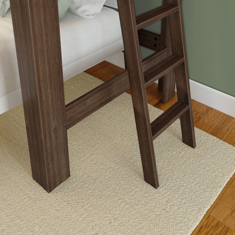 Wooden ladder leaning against a bed on a textured rug in a cozy bedroom setting.