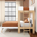 Space-saving wooden loft bunk bed with ladder, rust brown bedding and white linens in a modern industrial bedroom with exposed brick wall and large grid window