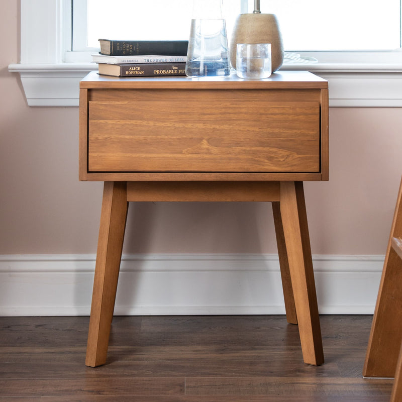Mid-century modern oak nightstand with single drawer and tapered legs, styled with books, glass carafe and table lamp for minimalist bedroom decor