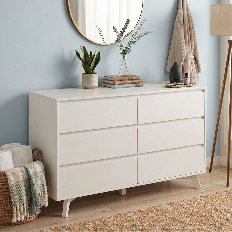 White mid-century dresser with round gold mirror, snake plant in ceramic pot, eucalyptus vase, woven basket and neutral robe — modern Scandinavian bedroom decor