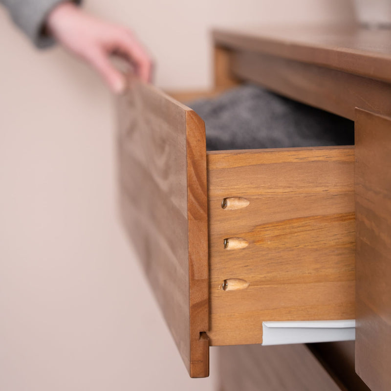 Hand opening a mid-century wooden dresser drawer with visible wooden dowel joinery and folded clothing inside