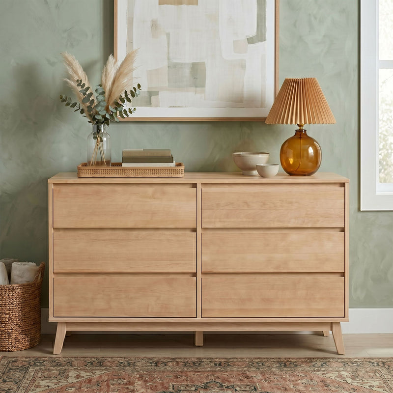 Light wood mid-century dresser against sage green wall with pampas grass vase, amber glass lamp, stacked books and neutral decor — modern minimalist bedroom storage and styling